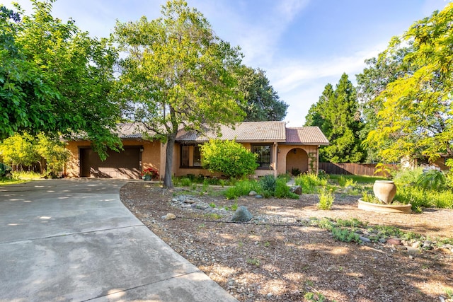 ranch-style home with a tile roof, a garage, fence, concrete driveway, and stucco siding