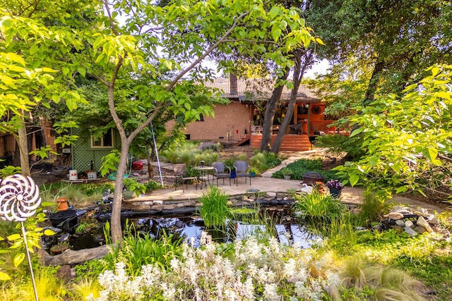 rear view of house featuring a garden pond, a wooden deck, a patio area, and stairway
