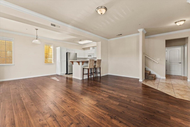 living area with wood-type flooring, visible vents, ornamental molding, and stairs