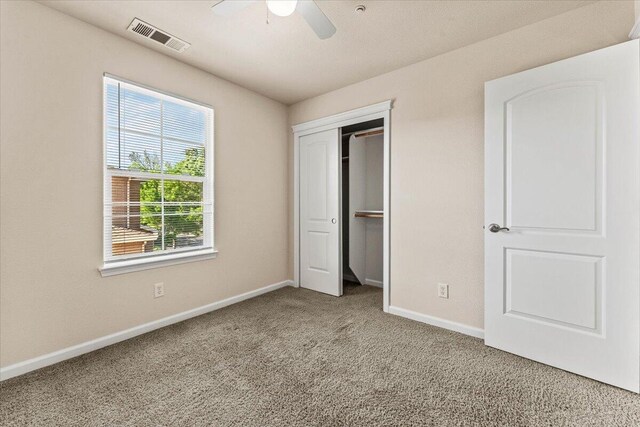 unfurnished bedroom featuring visible vents, a closet, baseboards, a ceiling fan, and carpet