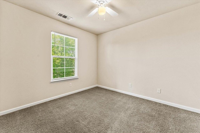 carpeted spare room with visible vents, baseboards, and ceiling fan