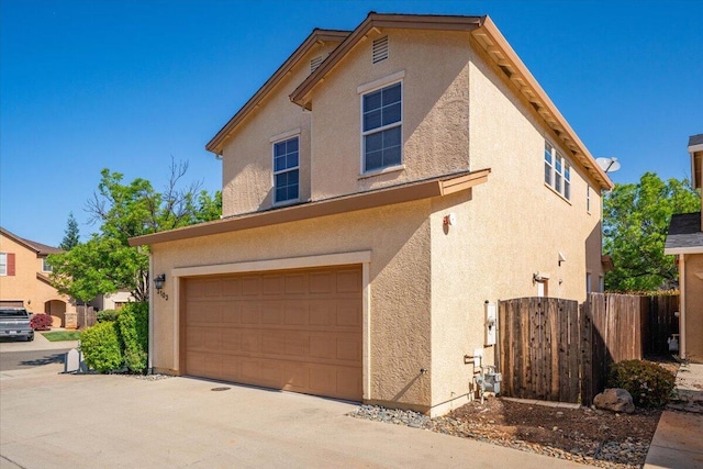 exterior space with a garage, stucco siding, and fence