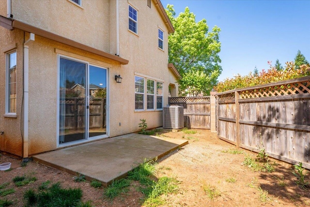 rear view of property featuring a fenced backyard, central AC unit, stucco siding, and a patio area