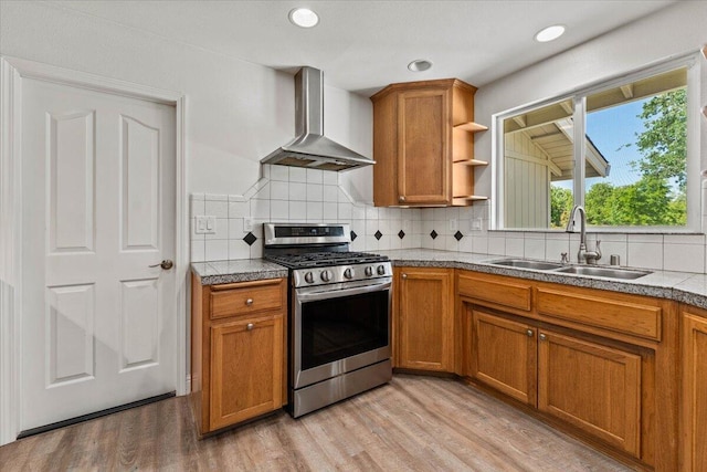 kitchen with a sink, wall chimney exhaust hood, brown cabinets, and gas stove
