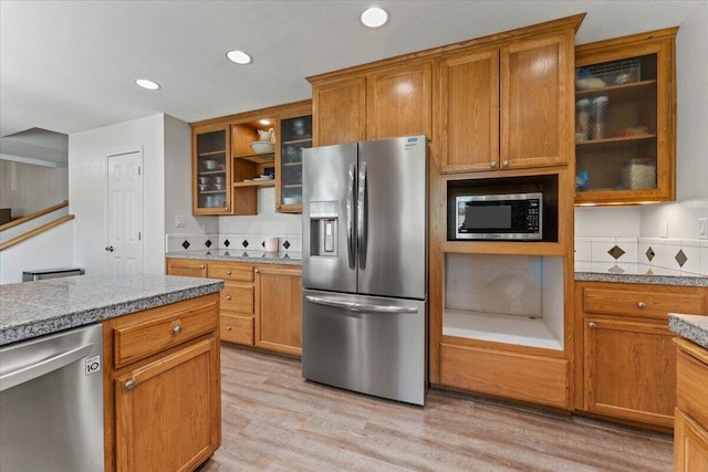 kitchen with recessed lighting, light wood-style floors, brown cabinets, and stainless steel appliances