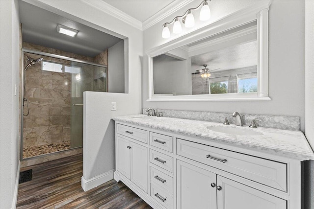 bathroom featuring a sink, ornamental molding, a stall shower, and wood finished floors