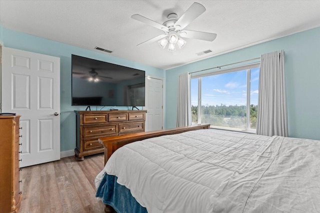 bedroom with visible vents, a ceiling fan, a textured ceiling, and wood finished floors