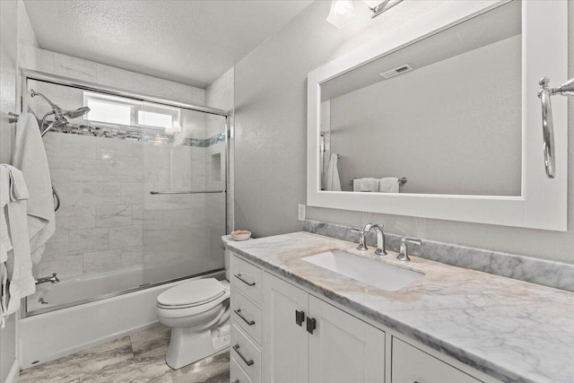 bathroom featuring a textured ceiling, visible vents, vanity, bath / shower combo with glass door, and toilet
