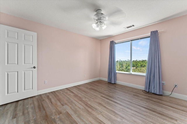 unfurnished room with visible vents, wood finished floors, baseboards, ceiling fan, and a textured ceiling