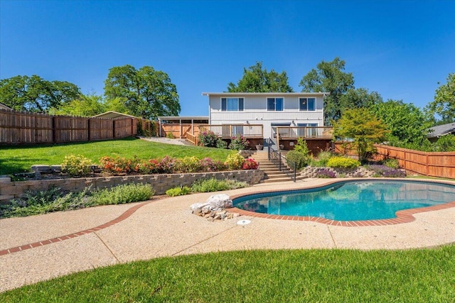 view of swimming pool with a lawn, a fenced backyard, a wooden deck, and stairway
