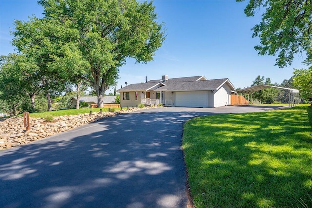 view of front facade with a detached carport, a garage, a front yard, and aphalt driveway