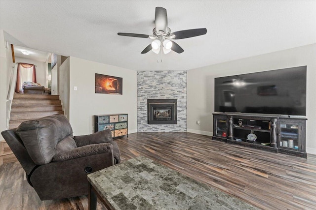 living room featuring a fireplace, a ceiling fan, baseboards, wood finished floors, and stairway