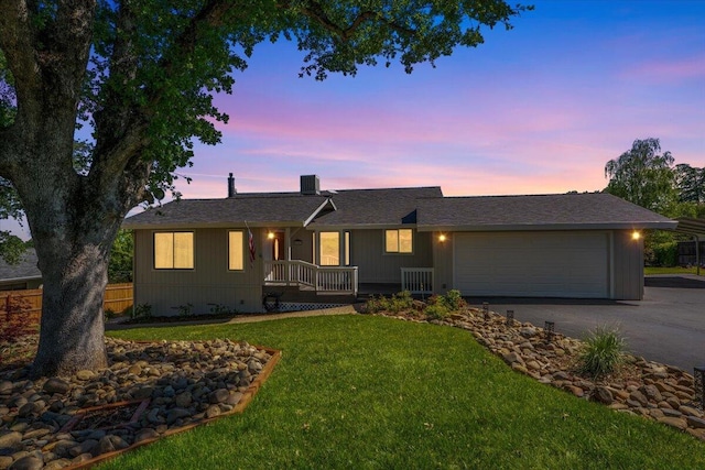 ranch-style home with covered porch, driveway, a garage, fence, and a front lawn