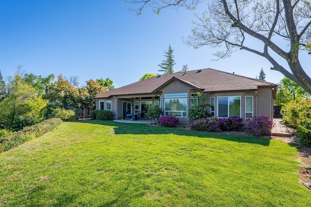 rear view of house featuring a patio area, stucco siding, a yard, and fence