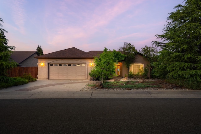 single story home featuring a garage, stucco siding, fence, and concrete driveway
