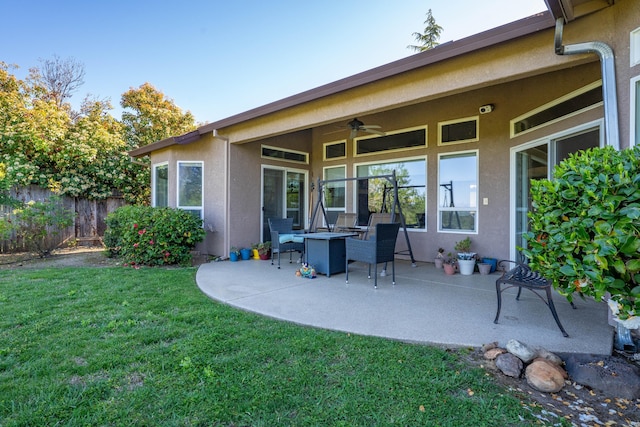 back of house with fence, stucco siding, ceiling fan, a patio area, and a lawn