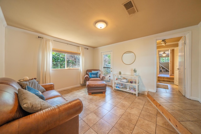 living area featuring light tile patterned floors, baseboards, ornamental molding, and visible vents