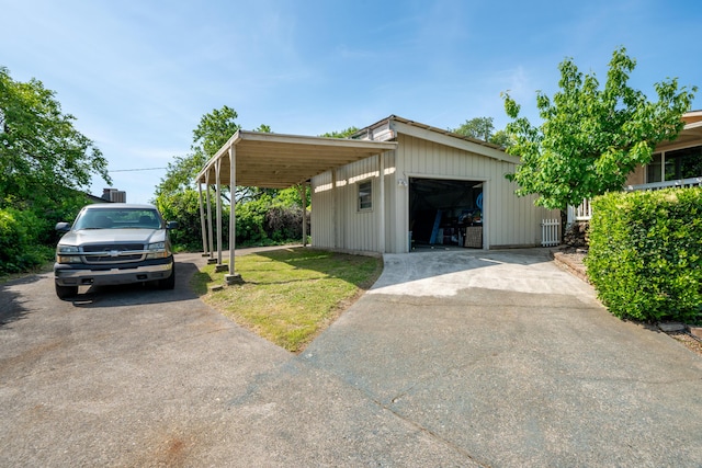 view of front facade featuring a detached garage, concrete driveway, an outbuilding, and a front lawn