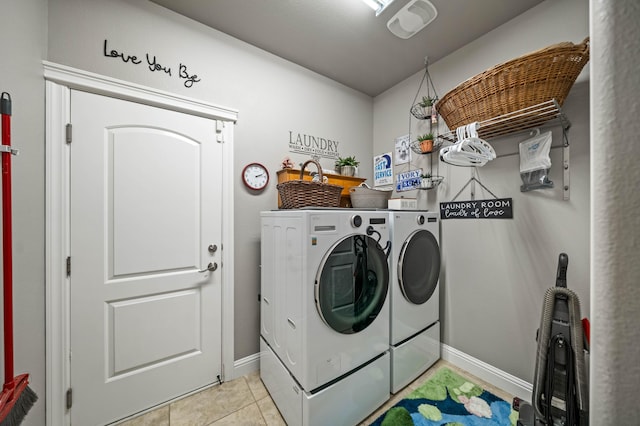 laundry area featuring light tile patterned floors, baseboards, laundry area, and washing machine and clothes dryer