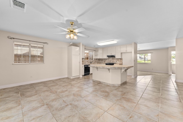 kitchen with light countertops, black dishwasher, light tile patterned floors, backsplash, and visible vents