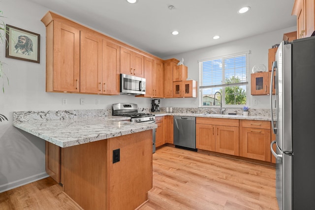 kitchen featuring a peninsula, a sink, light wood-style floors, appliances with stainless steel finishes, and recessed lighting