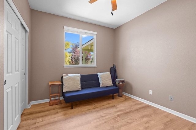 sitting room with baseboards, light wood-style floors, and ceiling fan