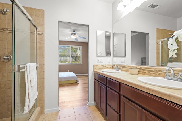 bathroom featuring double vanity, tile patterned flooring, a stall shower, and a sink