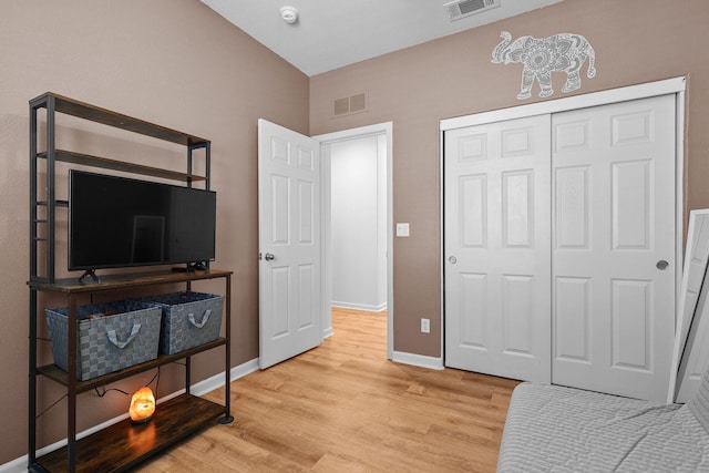 bedroom with a closet, light wood-type flooring, visible vents, and baseboards