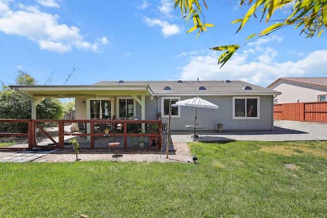 back of property with a yard, a patio area, stucco siding, and a fenced backyard