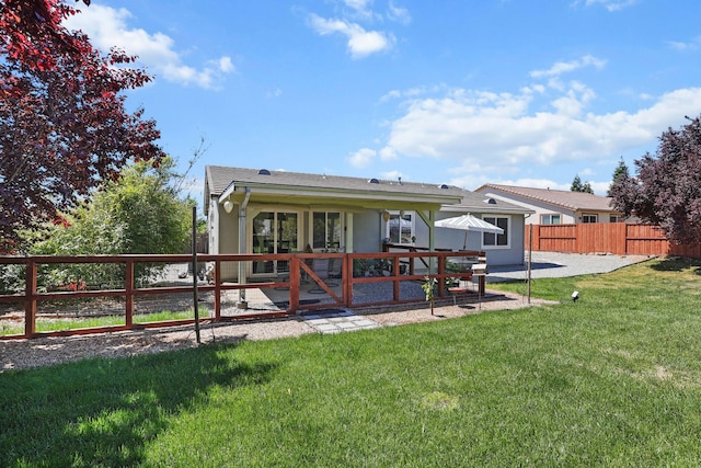 rear view of house with a fenced backyard, a patio area, and a yard