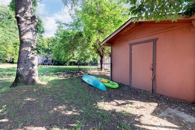 view of yard with a trampoline and fence