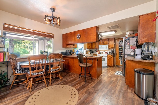 kitchen with brown cabinets, white appliances, light wood-style flooring, a peninsula, and visible vents