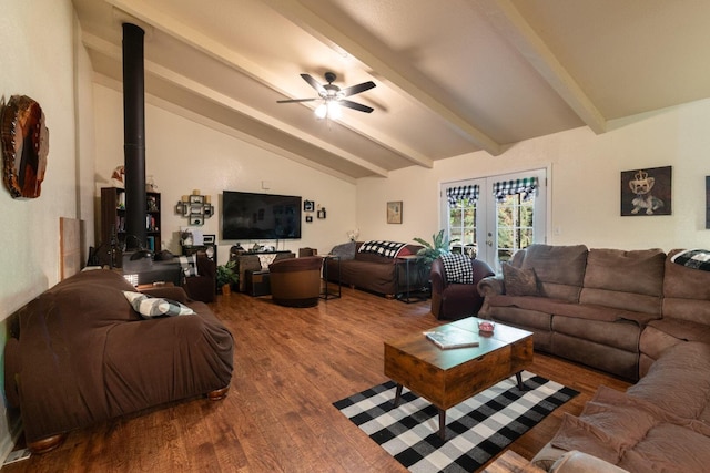 living room with a wood stove, wood finished floors, ceiling fan, vaulted ceiling with beams, and french doors