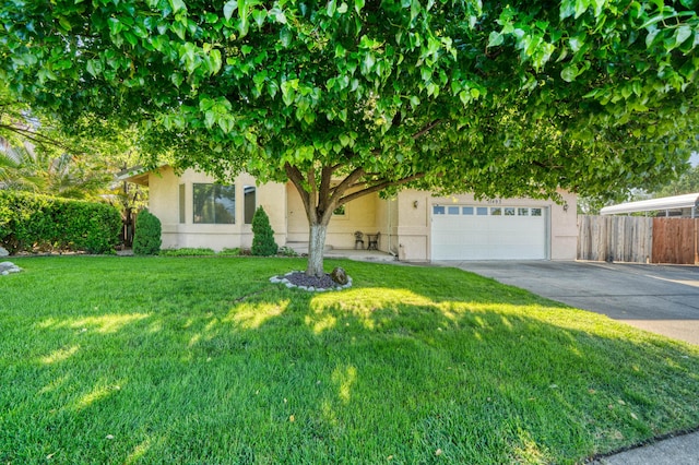 obstructed view of property with fence, driveway, a front yard, and stucco siding