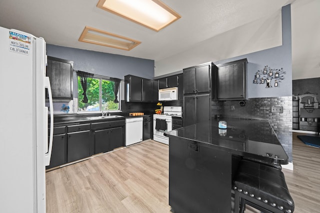 kitchen with dark countertops, white appliances, dark cabinets, a sink, and backsplash