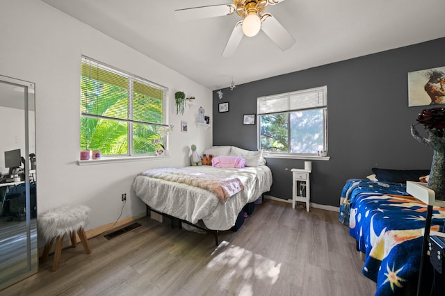 bedroom with baseboards, a ceiling fan, wood finished floors, and visible vents