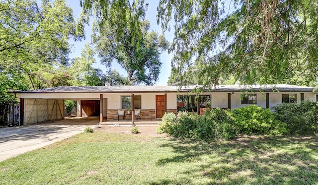 ranch-style home with a front lawn, stucco siding, an attached carport, a porch, and driveway