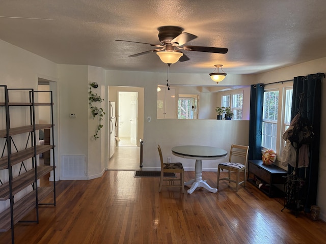 dining room featuring ceiling fan, a textured ceiling, baseboards, wood finished floors, and visible vents