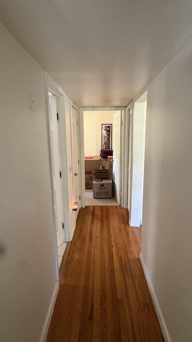 hallway with baseboards and wood finished floors