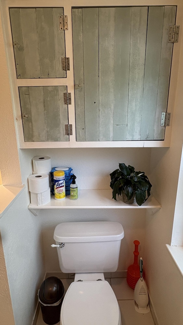 bathroom featuring baseboards, tile patterned flooring, and toilet
