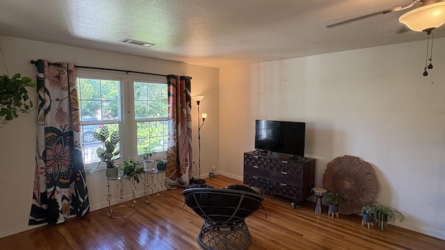 interior space with baseboards, a ceiling fan, wood finished floors, and visible vents