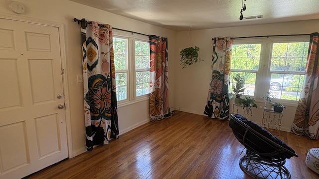 misc room with baseboards, wood finished floors, a healthy amount of sunlight, and visible vents