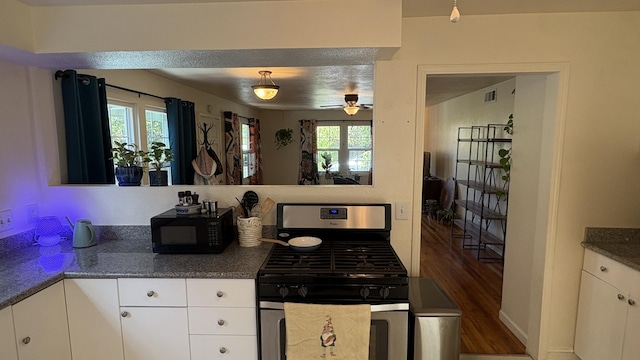 kitchen with gas stove, ceiling fan, black microwave, and white cabinetry