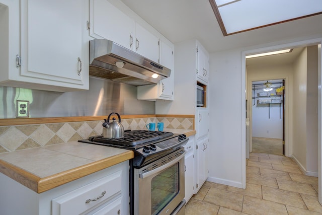 3140 Winding Way, Redding, CA 96003 - kitchen with under cabinet range hood, white cabinets, backsplash, light tile patterned floors, and stainless steel appliances
