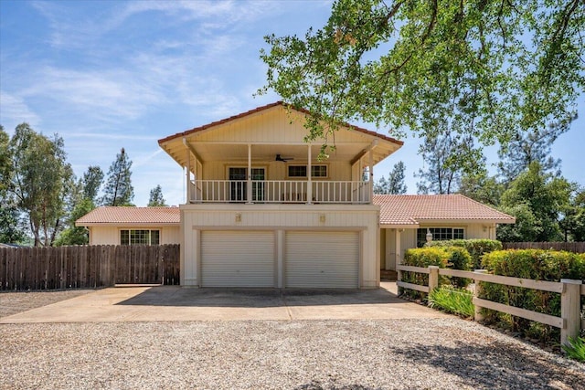 view of front of home featuring a tiled roof, driveway, ceiling fan, and a balcony