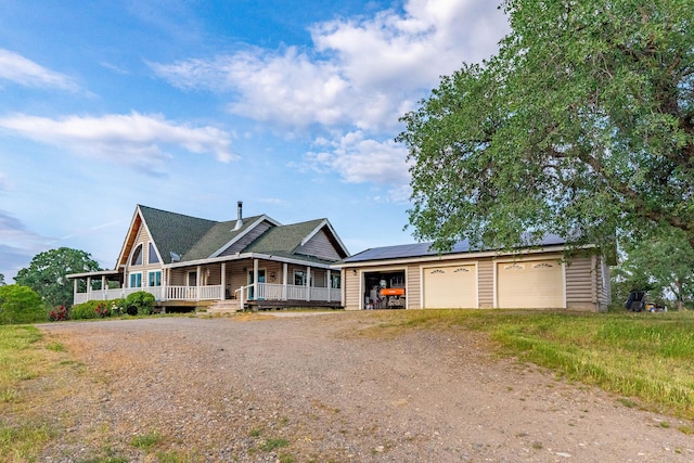 view of front of home with dirt driveway, a porch, solar panels, and a garage