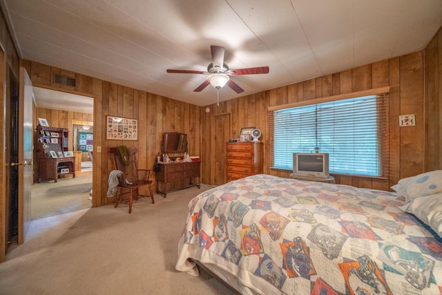 bedroom featuring light colored carpet, wood walls, a ceiling fan, and visible vents