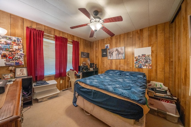carpeted bedroom featuring wood walls and a ceiling fan