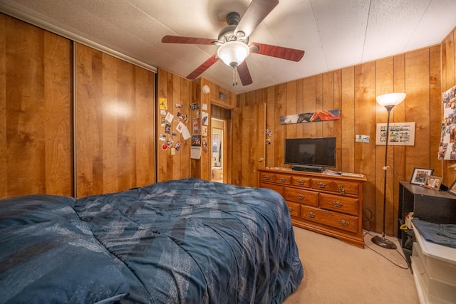 carpeted bedroom with wood walls and a ceiling fan