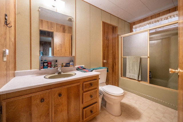 full bath with toilet, enclosed tub / shower combo, wooden walls, tile patterned floors, and vanity